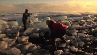 He was taking photos of the beautiful ice cubes with bare feet on the beach