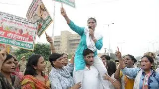 Mahila Congress chief Sushmita Dev sitting on a worker's shoulders during protest
