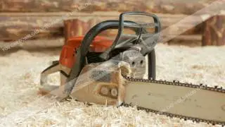 Chainsaw builder at the site of construction of a wooden house. Many sawdust and a part of the