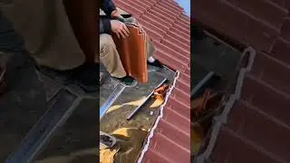 Man installing new terracotta brown ridge cap tiles on roof