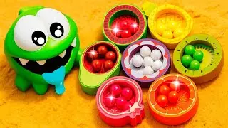 Om Nom juega con frutas y busca bolitas de colores en la arena