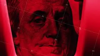 Close up of flare of red light illuminating hundred dollar banknote