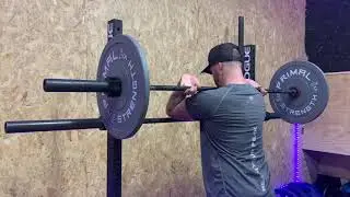 Standing lat and thoracic stretch using barbell in front rack position