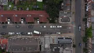 Aerial birds eye overhead top down tracking of white delivery van driving in street of town and
