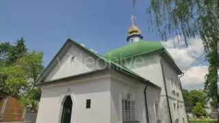 Car Driven by Green Roofed Church Courtyard Panorama Cityscape Road Sunny Day Flower Beds Trees and