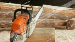 Chainsaw builder at the site of construction of a wooden house. Many sawdust and a part of the