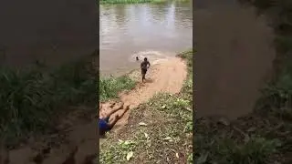 Rural kids sliding on the mud into a river.!