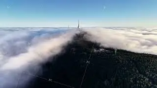 Foggy Mountain Crest Cast Dramatic Shadows, Sunlit Ridge Extends Through Fog With Distant Spire