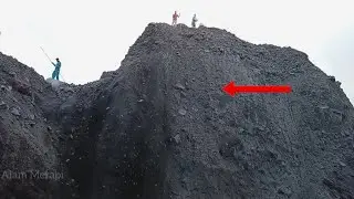 On a very high cliff the miners worked hard to slide sand and stone.