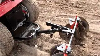 Garden tractor planting potato's with disk harrow