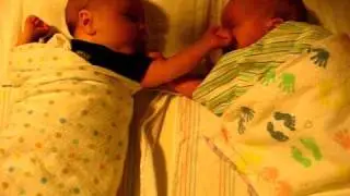 1-month old identical twin boys interacting in crib