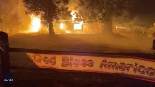 God Bless America sign blows with Dixie Fire in the background