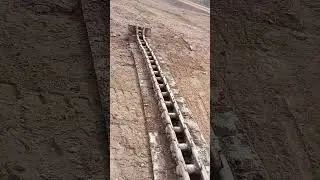 The chain of a Caterpillar 96D loader has come off and is scattered on the ground.