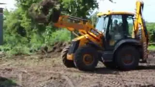 Экскаватор JCB 3CX Super загружает грунт в КАМАЗ
