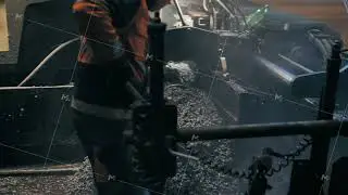 Road workers spread the asphalt with a shovel in front of an asphalt paver. Repair of a city road at