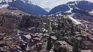 Panoramic view of Gstaad cityscape, nestled in the Swiss Alps, highlighting traditional chalets and