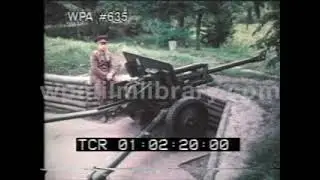 WWII veteran (Soviet army) wearing uniform and sitting in field by an antique howitzer