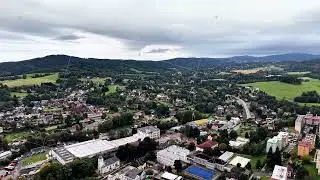 An aerial view displays a picturesque landscape with a charming town and rolling hills
