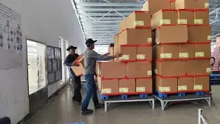 Workers are dumping cardboard boxes from a warehouse through a pipeline.