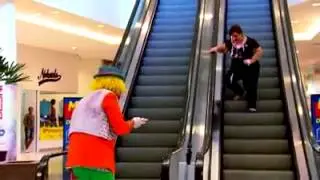 Payaso tira tarta a se�ora en escaleras mecanicas