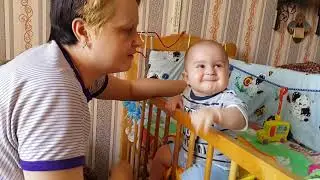 Играем в козу с мамой. Ваня свесил ножки между прутьями кроватки