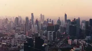 Expansive aerial view of Bangkok's bustling cityscape at sunset. High rise buildings and modern
