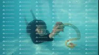 Scared woman taking snake from pool bottom underwater and throwing it in camera.