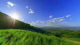 sun peeking over vibrant green hills  kmPC09xS
