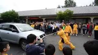 Shaolin Monk Pushing A Car With A Spear On His Neck
