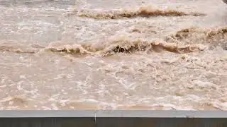 Car driving through flooded street causing huge splash on rainy day