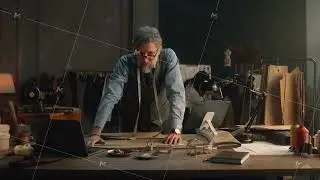 Tailor works in luxury atelier and looks at camera