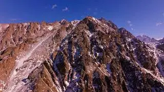Majestic snowy mountain peaks over rocky terrain in winter, drone view