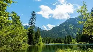 Cloud timelapse against blue sky, mountains and a lake in the European Alps
